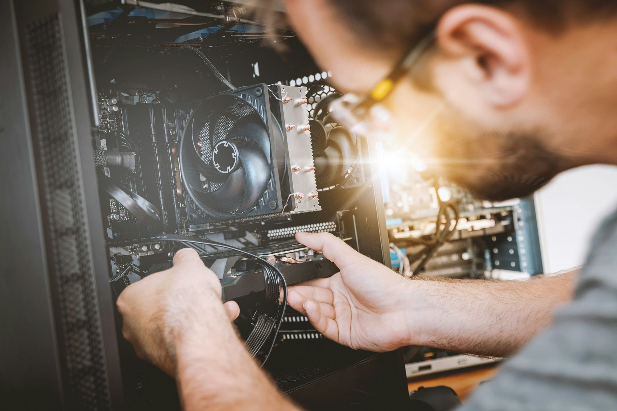 A technician working inside an open desktop computer
