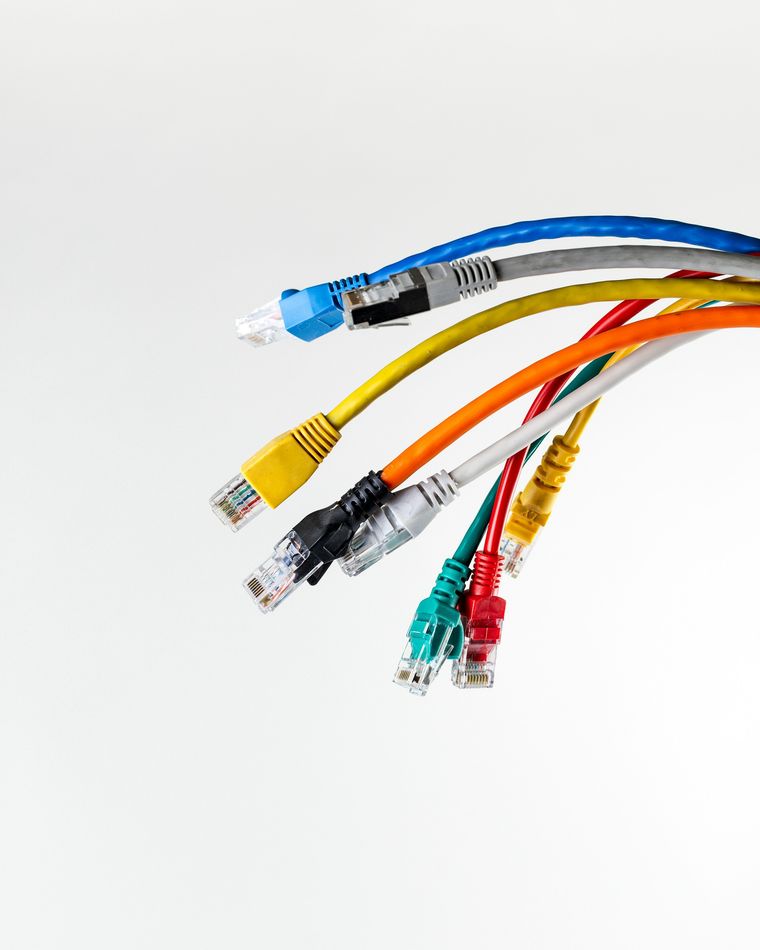 A fan of copper patch cords in blue, grey, yellow, orange, red, green and black, each terminated with an RJ45 plug.