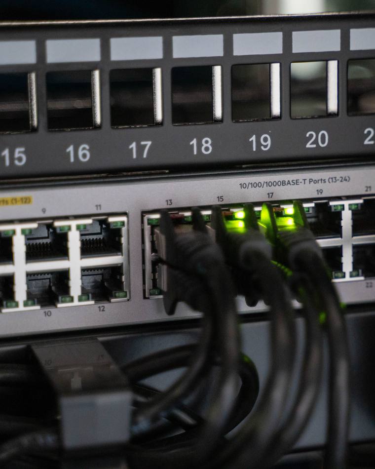 A numbered patch panel above a PoE switch, ports 13 to 24 labeled and link lights showing.